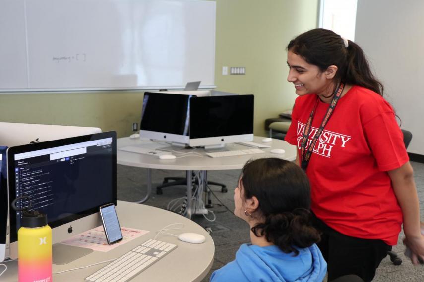 Volunteer assists an attendee at a computer.