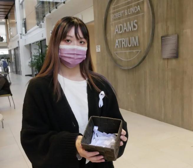 female student (Grace Ly) holding a basket of white ribbons