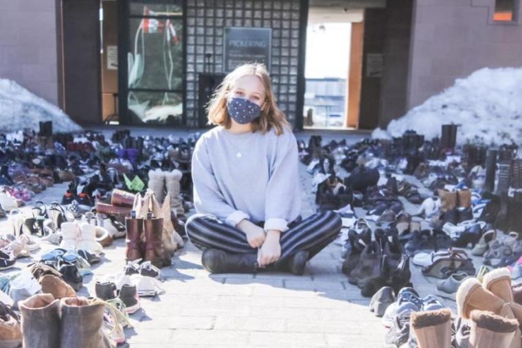 Ally Zaheer sitting amidst nearly 1,000 shoes placed outside city hall in Pickering in late February in protest to proposed development of provincially significant wetlands.