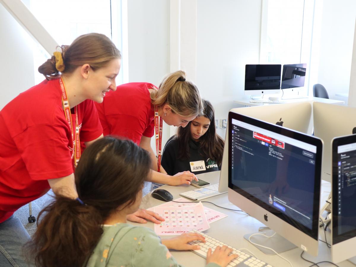 photo of two women helping a student on a computer 