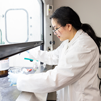 female student pouring liquid out of a beaker