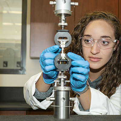 female student placing a biomaterial in a machine